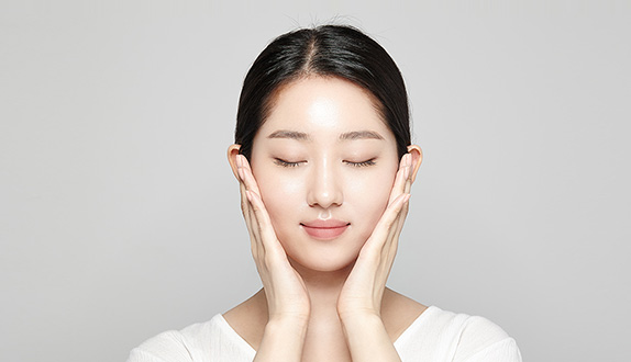 양 볼을 손으로 감싸고 있는 모델